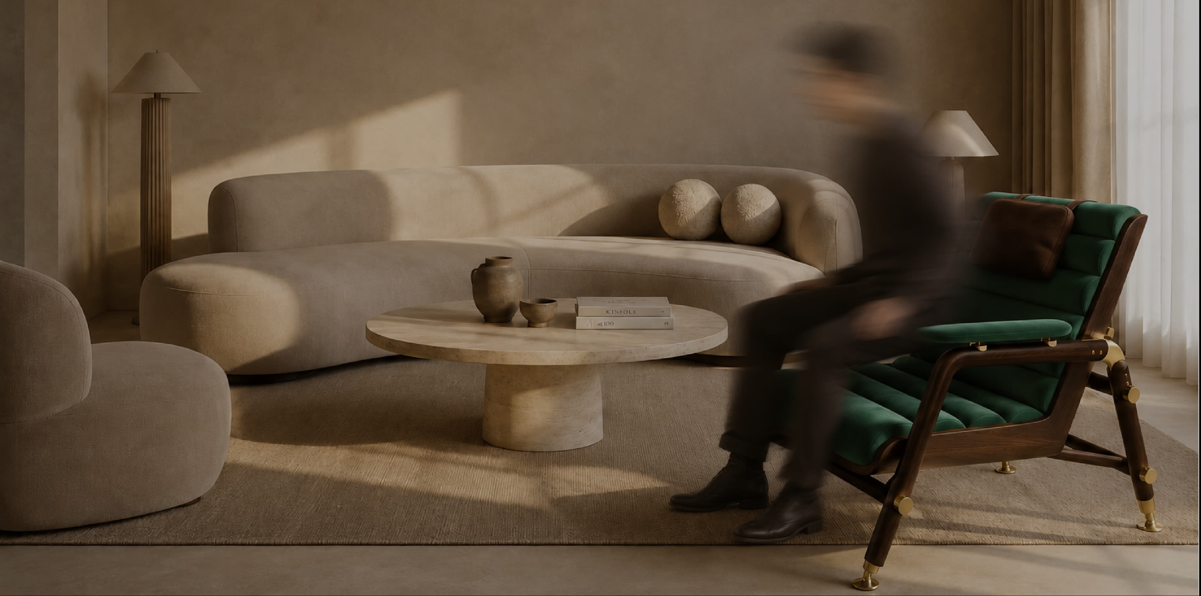 Warm living room with curved beige sofa, travertine coffee table and green velvet lounge chair