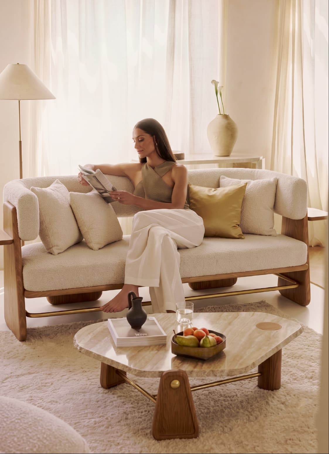 Woman reading on a bouclé sofa in a bright living room