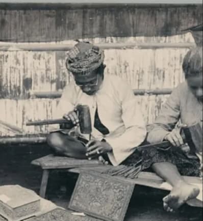 Archival photo of Balinese carvers chiselling ornate wooden panels