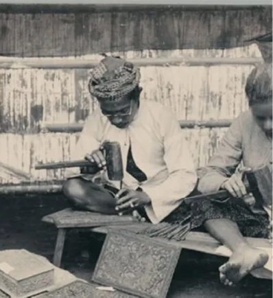 Archival photo of Balinese carvers chiselling ornate wooden panels
